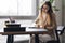 Beautiful female sitting at table near window, makes notes in notebook. The young specialist conducts research on serious