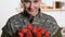 Beautiful female soldier holding red tulips smiling on camera, armed forces day