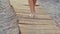 Beautiful female tanned feet walking along wooden walkway on beach. girl walks on beach