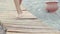 Beautiful female tanned feet walking along wooden walkway on beach. girl walks on beach