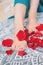 Beautiful female tanned legs with pink pedicure among rose petals, close-up