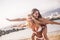 Beautiful females young friends have fun together carrying eachother at the beach with sea in background. summer vacation and