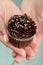 Beautiful feminine hand holding tasty appetizing chocolate cupcake. Blue Background. Closeup.