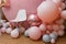 Beautiful festive decorations, pink and grey balloons, white chair on wooden round background. Little 1 year old girl birthday