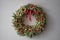 Beautiful festive wreath of fresh spruce on Gray wall. Xmas circlet with red and gold ornaments and balls. Christmas