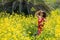 A beautiful field of tall plants and yellow flowers and a young woman with a Bicycle