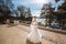 A beautiful figured bride strolls along the quay and admires the hills and the blue sunny sky.