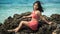 Beautiful Filipina in a red swimsuit posing on a beach rock in Capitancillo Island, Bogo city
