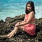 Beautiful Filipina in a red swimsuit smiling and posing on a beach rock in Capitancillo Island