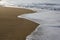 Beautiful filled frame close up seascape wallpaper background shot of golden orange sand with white foamy waves of the Indian