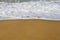 Beautiful filled frame close up seascape wallpaper background shot of golden orange sand with white foamy waves of the Indian