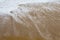 Beautiful filled frame close up seascape wallpaper background shot of golden orange sand with white foamy waves of the Indian