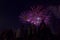 Beautiful firework scene with people as silhouttes watching at the colorful violett rockets at the night sky.