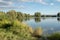 Beautiful fish pond in Badin, near Banska Bystrica, Slovakia. Trees mirror reflection in the water. Fishing place. Shining sun