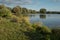 Beautiful fish pond near Badin, Banska Bystrica, Slovakia. Sky and trees mirror reflection in the water. Fishing place. Shining