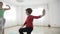 Beautiful fit female instructor teaching a little girl standing still yoga poses in slow motion in a bright gym studio -