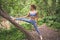 Beautiful fit woman in sportswear doing stretching exercises using a tree trunk. Muscular slim attractive girl with flat belly in