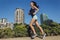 Beautiful fitness girl running in the city with urban background of skyscrapers
