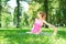 Beautiful fitness lady practicing yoga stretching on the lawn in a city park