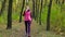 Beautiful fitness sport girl walking along the autumn park in sportswear with sports water bottle or isotonic drink in hand.