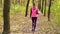 Beautiful fitness sport girl walking along the autumn park in sportswear with sports water bottle or isotonic drink in hand.