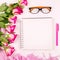 Beautiful flat lay with flowers, glasses, opened notebook and a pen, concept of a woman`s workplace