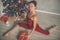 Beautiful flexible sportive woman is sitting in split near decorated christmas tree, sports and holiday concept