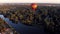 Beautiful flight at the sunrise of a red balloon over a river, forest, green trees