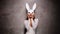 Beautiful flirting Asian woman in white dress and rabbit mask playfully posing for camera in the spotlight