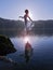 Beautiful Floating Girl dressed in white, silhouetted by the sun reflected in still lake