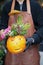 Beautiful flower arrangement of pumpkin and fuchsia roses for Halloween celebration in florist hands.