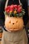 Beautiful flower arrangement of pumpkin and tomato color red roses for Halloween celebration in florist hands.