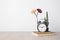 Beautiful flower in vase and alarm clock, book, pencil on wood