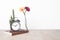 Beautiful flower in vase and alarm clock, book, pencil on wood