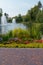 Beautiful flowers growing in a flower bed next to a path of tiles in a park on a background of fountains in a pond.