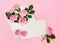 Beautiful flowers pink roses in postal envelope, pink hearts and blank sheet with space for text on a pink paper background.