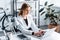 Beautiful focused businesswoman in formal wear sitting at desk and typing on laptop