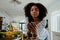 Beautiful focussed female researching recipe on smartphone standing next to chopped vegetables in organised kitchen.