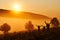 Beautiful fog in the morning. Silhouettes of three people - dad and two children against a beautiful golden sunrise. Hills in the