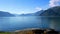 Beautiful footage of serene fjord and mountain landscape with blue water and sky, and birds on the rocky shore in the foreground