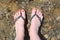 Beautiful foots of young woman wearing in flip flops, top view.