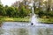 Beautiful fountain in the midst of a spring pond against the backdrop of a picturesque city park