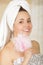 Beautiful fresh young girl wearing towel holding pink loofah body sponge