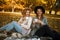 Beautiful friends spending time on a picnic blanket on the grass. Two young carefree smiling sisters making picnic eating fruits a