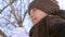 Beautiful frozen girl drinking tea from transparent glass in open air.