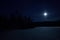 Beautiful full moon lights up snowy winter field