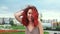 Beautiful funny girl with red curly waving hair turning around at sky background slow motion