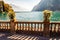 Beautiful Garda lake promenade with classic stone fence railings built on the edge with flowerpots with blooming white flowers.