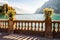 Beautiful Garda lake promenade with classic stone fence railings built on the edge with flowerpots with blooming white flowers.