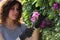 Beautiful gardener woman cutting flowers with secateurs